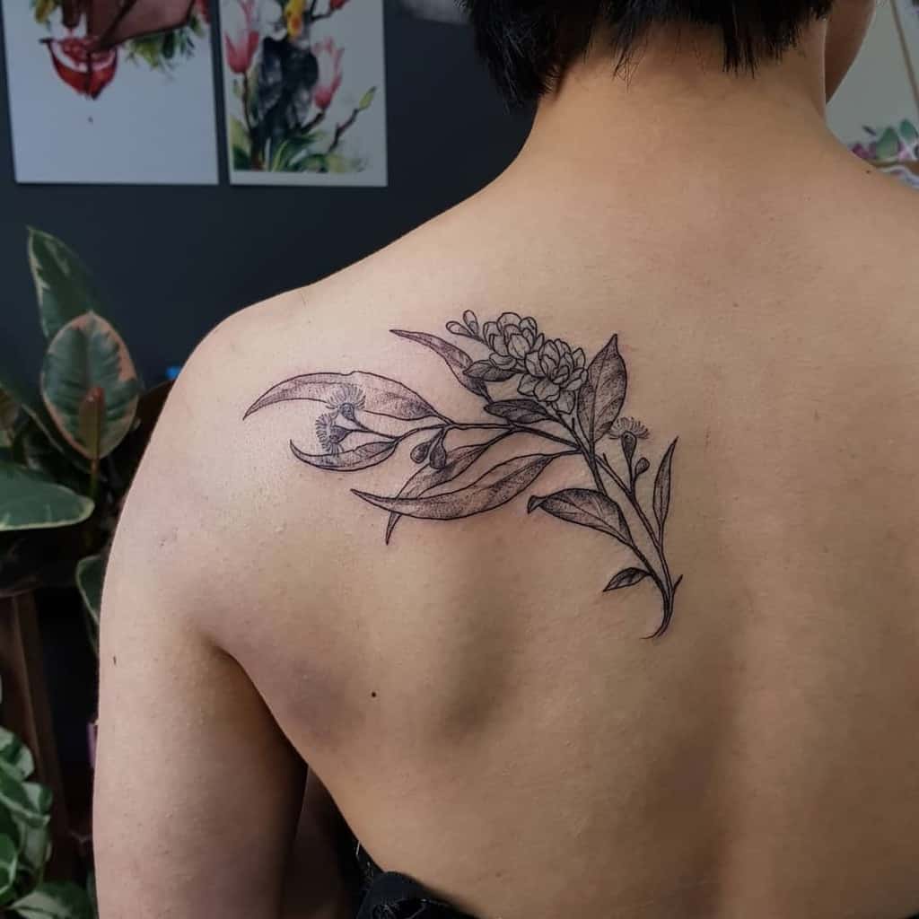 An individual with a black jasmine floral tattoo on their upper back