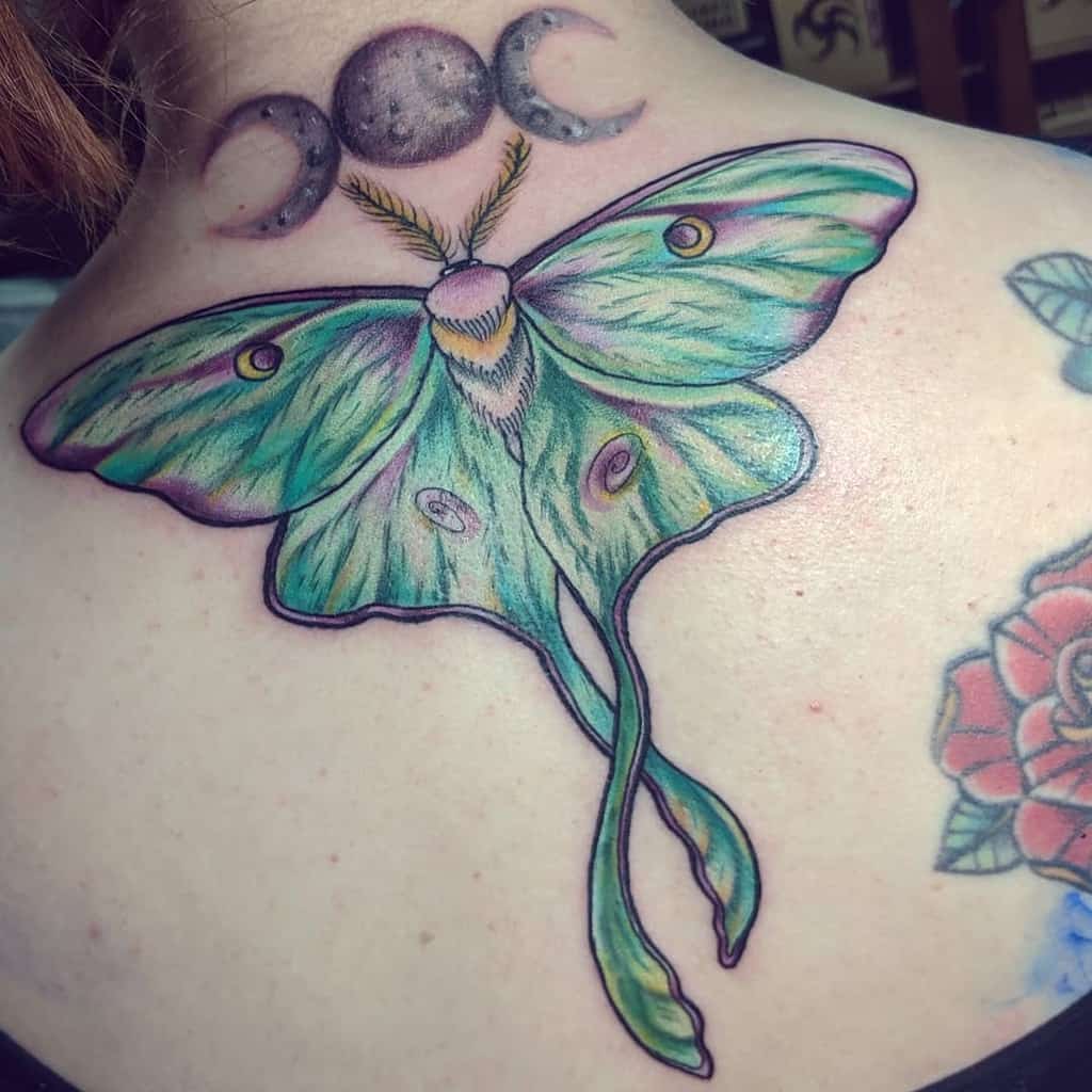 A colorful Luna Moth tattoo, featuring shades of green and blue, with a 2 crescent moon and full moon above the moth