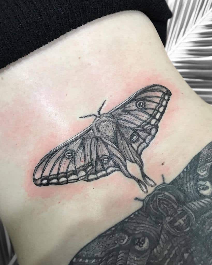 A detailed black and grey tattoo of a Luna Moth with intricate wing patterns and shading