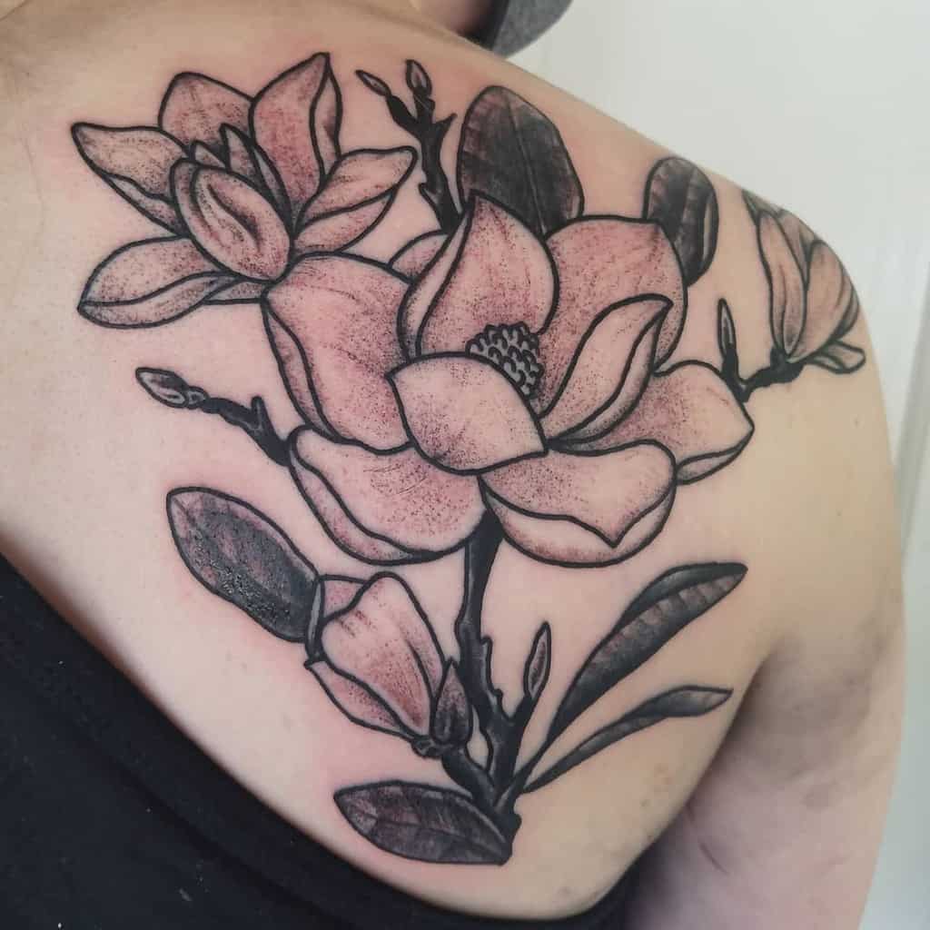 A stunning black and white tattoo of a magnolia flower graces the person's back
