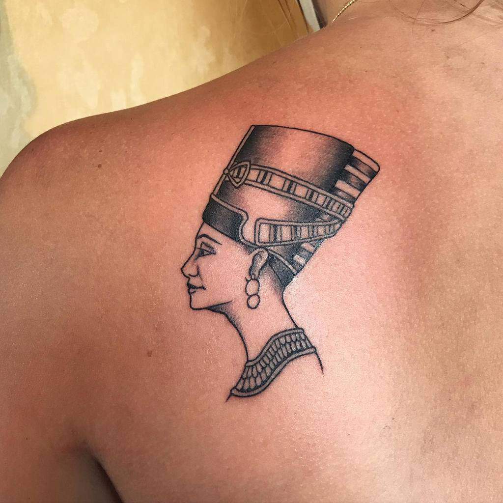 Back tattoo of Queen Nefertiti, showcasing fine black line work and intricate details on her iconic crown and jewelry