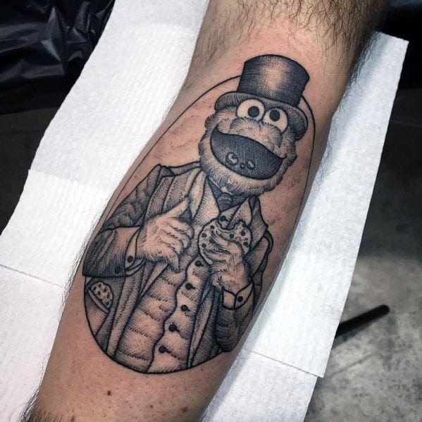 Victorian-style black and grey Cookie Monster tattoo wearing a top hat and suit, proudly holding a cookie with elegance.