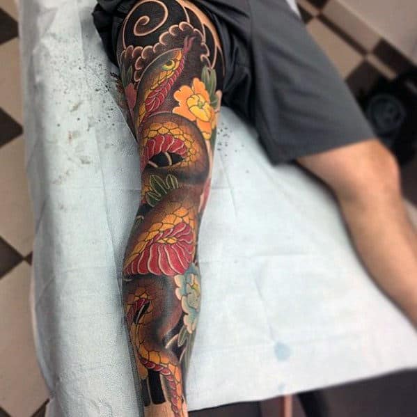 Leg tattoo with vibrant snakes, flowers, and dark intricate patterns