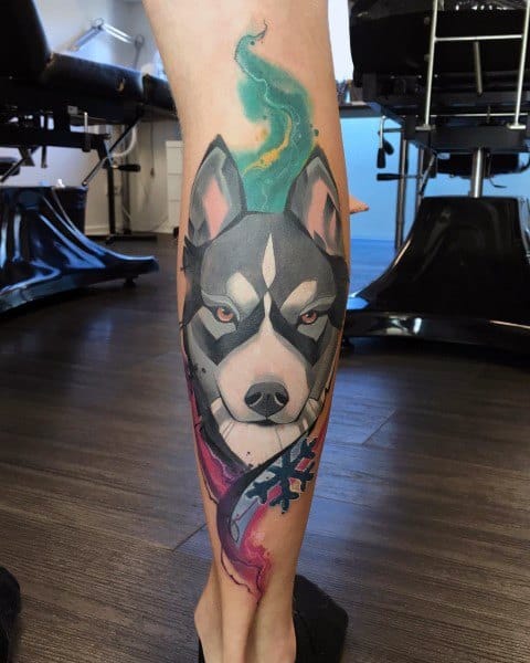 Neo-traditional Siberian Husky tattoo on a man's leg, featuring bold shading, vibrant watercolor accents, and dynamic abstract elements.