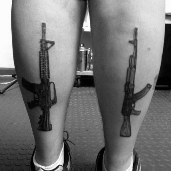 Black and grey AR-15 and AK-47 tattoos on the back of both legs, symbolizing balance, strength, and appreciation for iconic firearms.