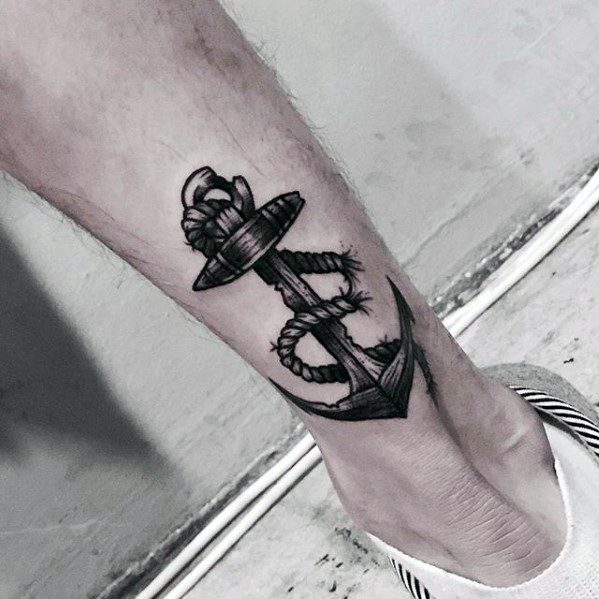 A black anchor tattoo with a rope design on the calf of a person's leg