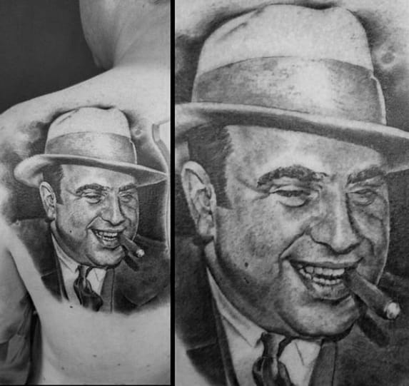 Al Capone tattoo on the back, featuring a detailed black-and-white portrait of the gangster smiling with a cigar and wearing his signature fedora.