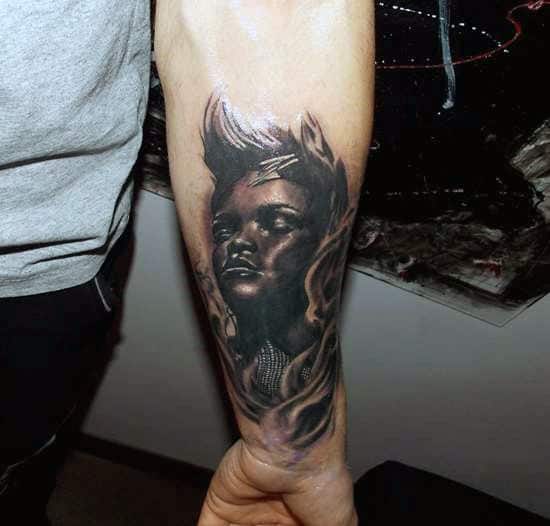 Forearm tattoo of a realistic face with artistic flame-like elements around it