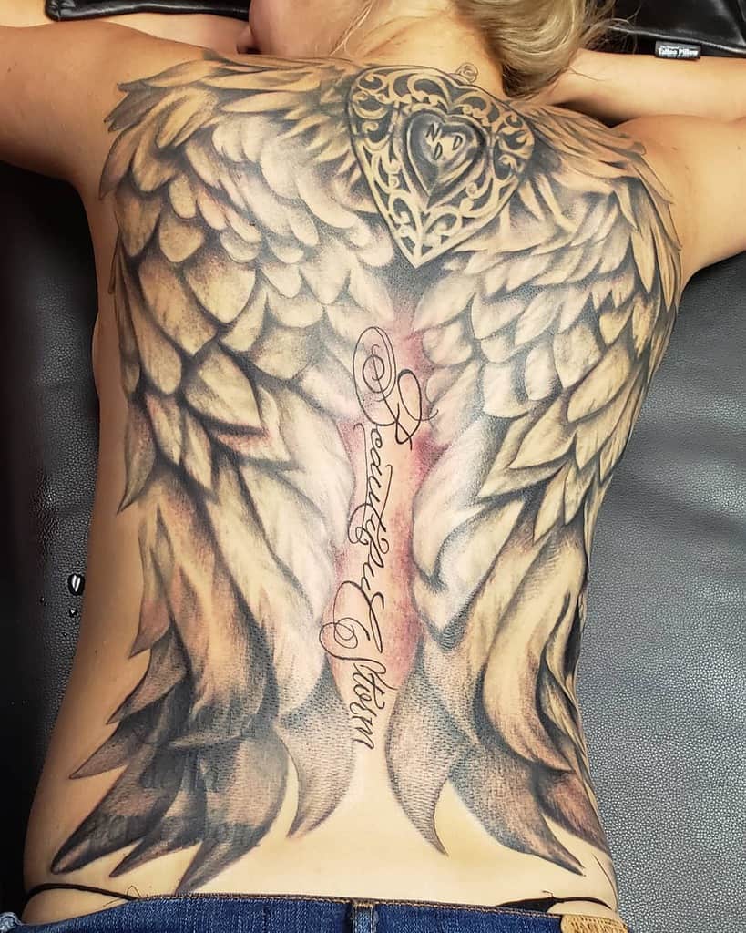 A large angel wing tattoos, featuring a heart design and script text in the center