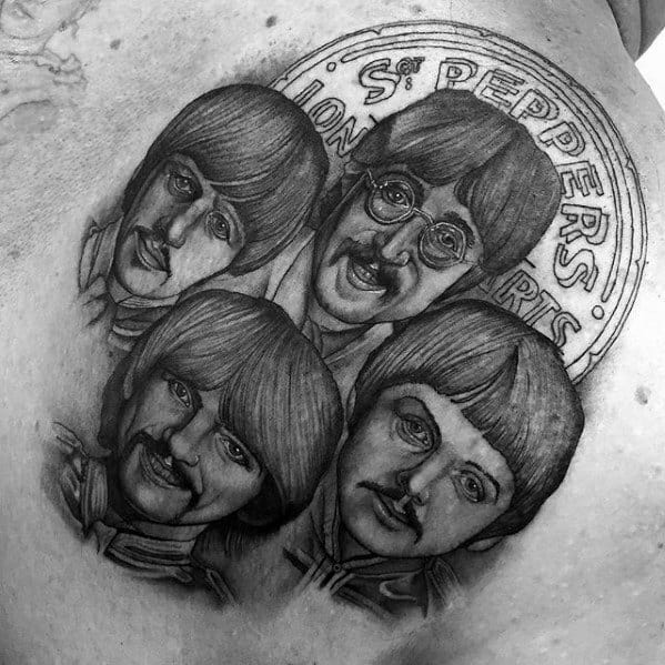 Detailed black and gray tattoo of The Beatles in their Sgt. Pepper’s Lonely Hearts Club Band outfits, with the album title in the background.