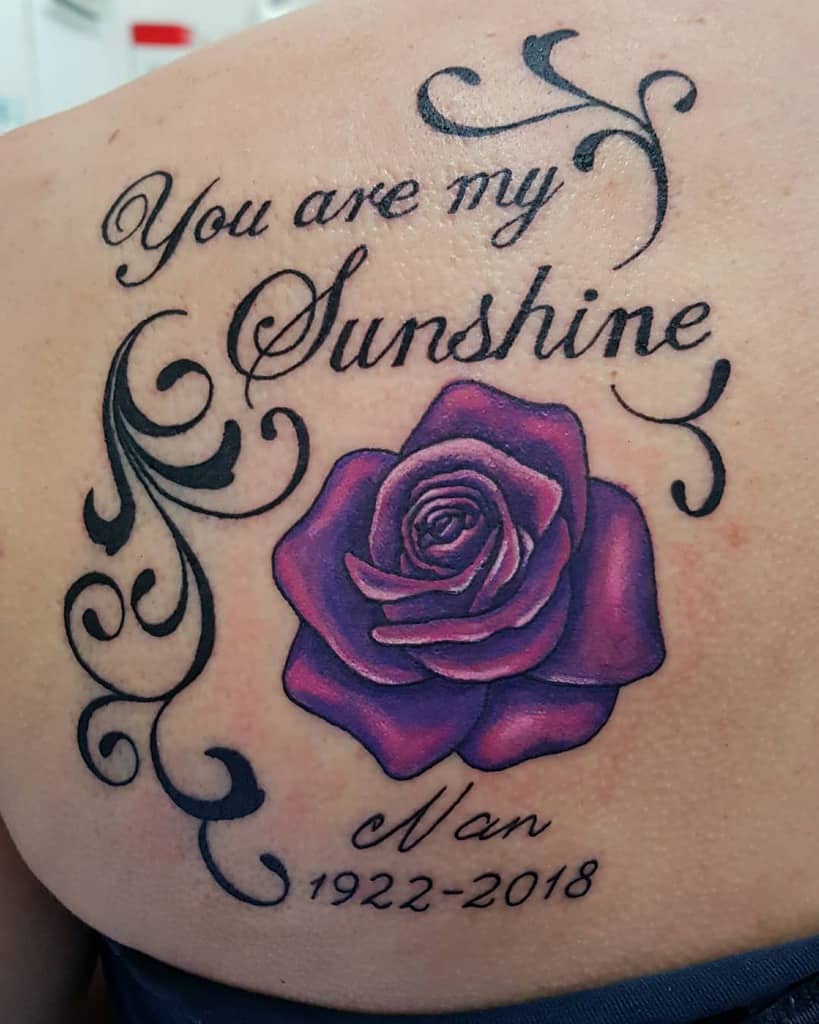 A tattoo featuring the heartfelt message "You are my sunshine" beautifully intertwined with a delicate purple rose, alongside a tribute to "Nan 1922-2018"