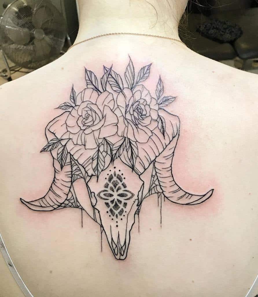 Tattoo of a ram skull with roses on top, inked on the upper back