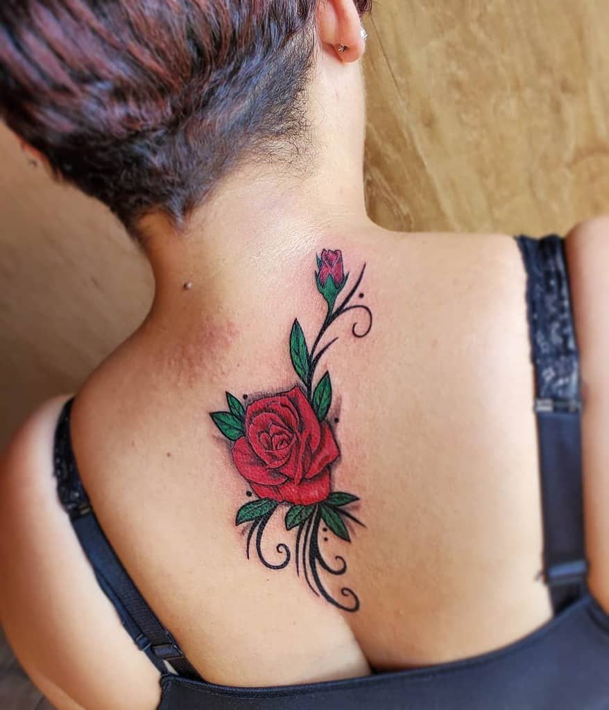 A woman with a vibrant red rose tattoo graces her upper back