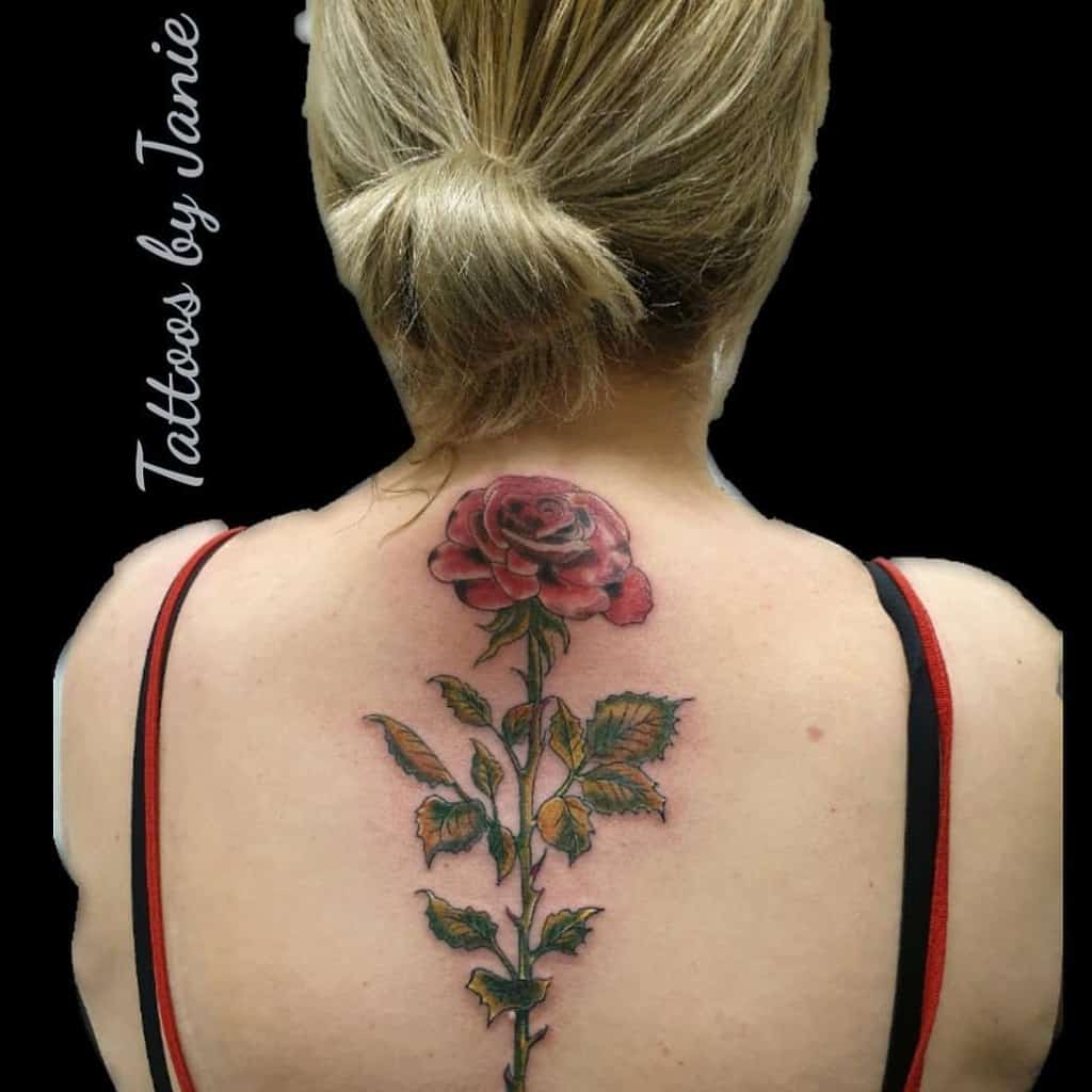 Back tattoo of a red rose with leaves and an elegant stem