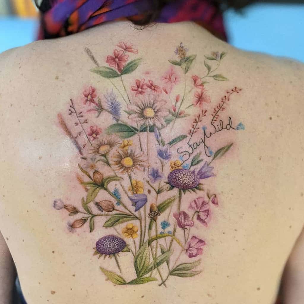 Colorful floral tattoo with the words "Stay Wild" on an upper back