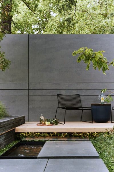 Enclosed concrete fence wall with modern outdoor seating and small garden.