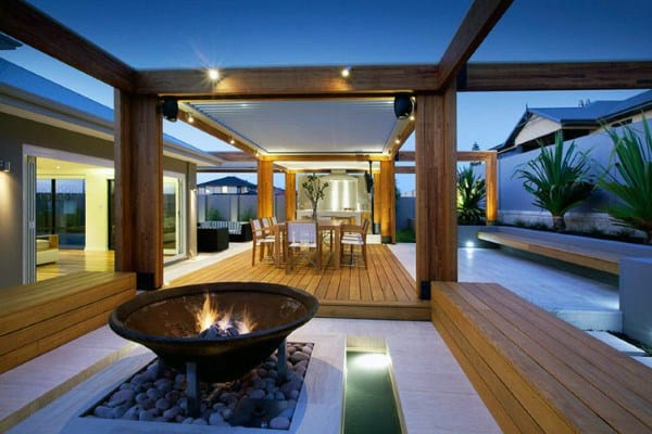 Modern backyard deck with firepit, pergola, and outdoor dining area at dusk.