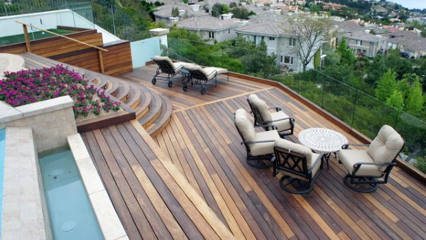 Tiered wooden deck with lounge chairs, outdoor seating, flower beds, and a scenic neighborhood view.