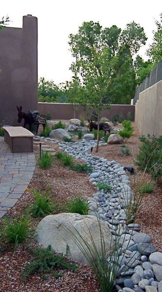 Peaceful backyard design with a river rock pathway, surrounded by plants, rocks, and a bench in a serene landscape