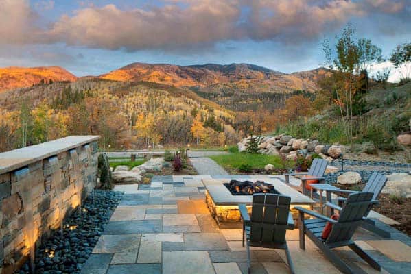 Mountain view with a stone patio, Adirondack chairs, and a fire pit surrounded by autumn-colored trees