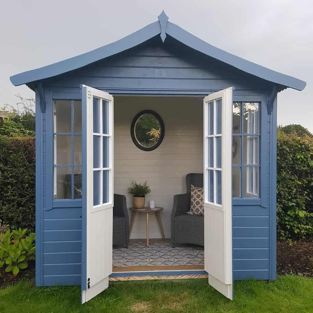 small blue shed with wicker chairs and gold table wall mirror