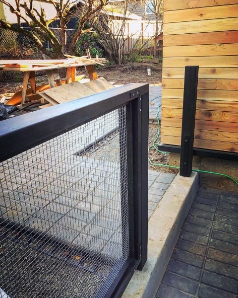 Contemporary wire mesh barrier with a black metal frame adjacent to a wooden deck.
