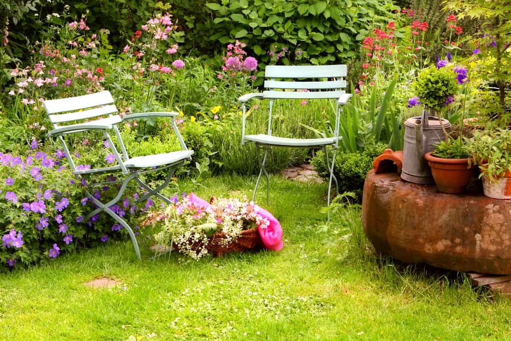 backyard flower garden two chairs watering can