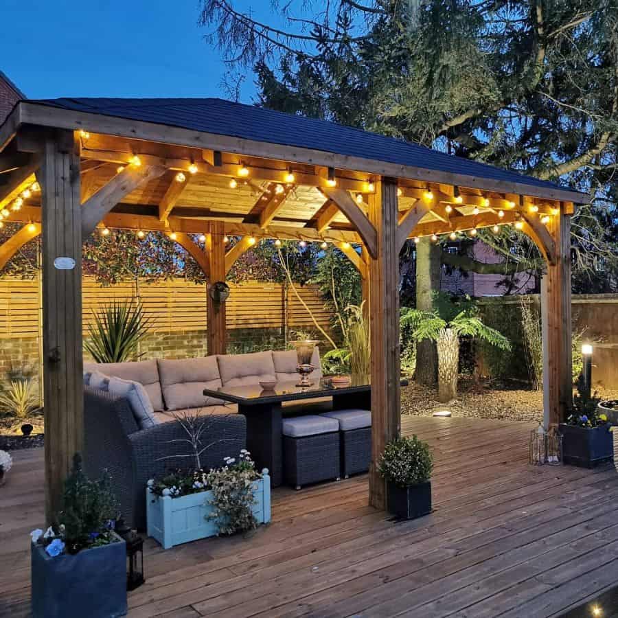large backyard wood gazebo and deck wicker sofa glass tabletop string lights plants