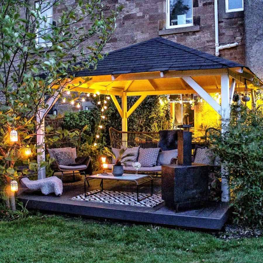 backyard wood gazebo tile roof wood deck wicker furniture hanging lights