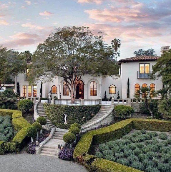 Grand staircase with lush landscaping on a sloped yard, featuring topiary shrubs, lavender bushes, and elegant architectural details