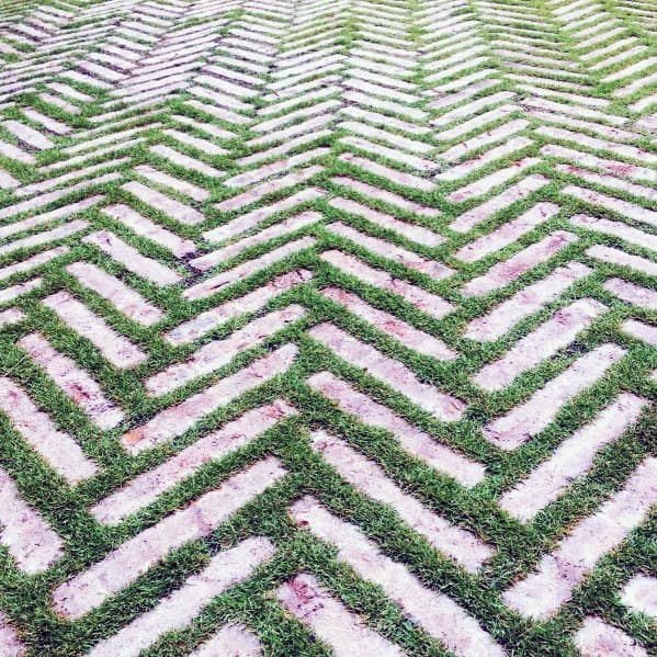 A geometric pattern with green grass and white stone in a zigzag design, complemented by brick accents
