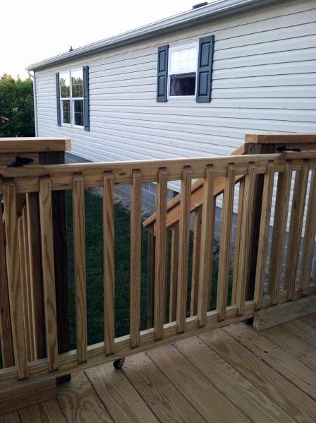 Wooden deck with railing, stairs, and gate leading to a white house with green shutters