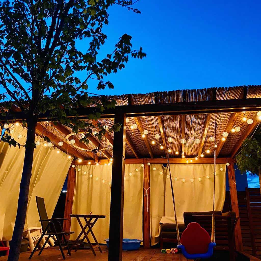wood deck patio pergola with string lights and curtains