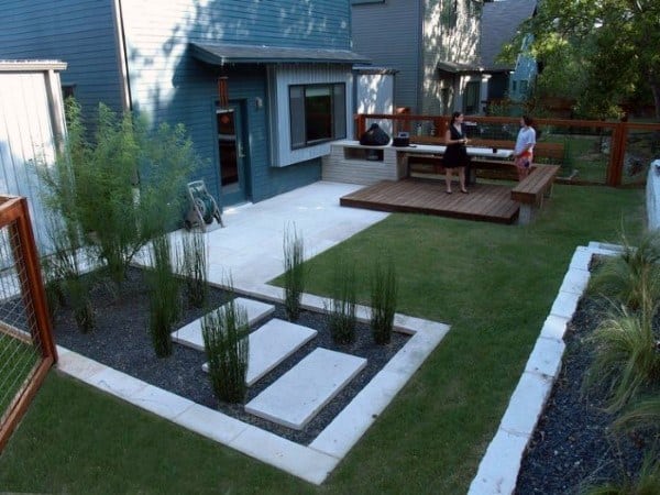 Modern backyard with concrete steps, grass lawn, wooden deck, and outdoor dining area.