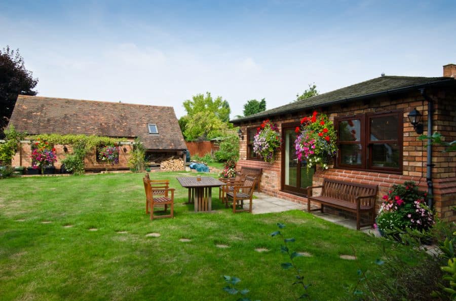 large backyard with small patio and wood furniture