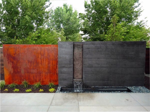 Modern backyard waterfall with sleek black and rust-colored panels and a minimalist design.