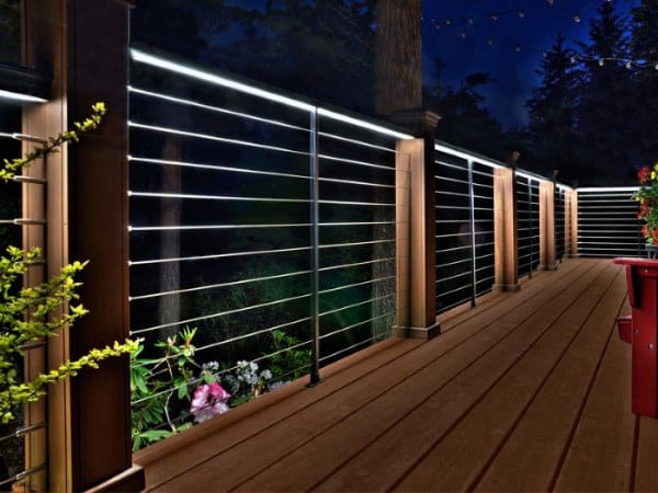 Wooden deck with cable railing and integrated LED lighting at night.