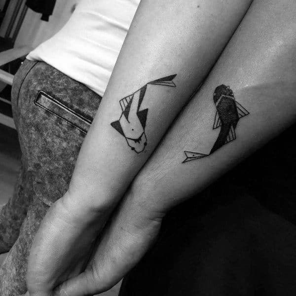 Matching geometric koi fish tattoos on forearms, symbolizing balance, harmony, and a deep bond between the couple.