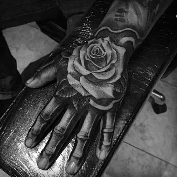 A stunning black and white tattoo of an intricately detailed rose graces the person's hand