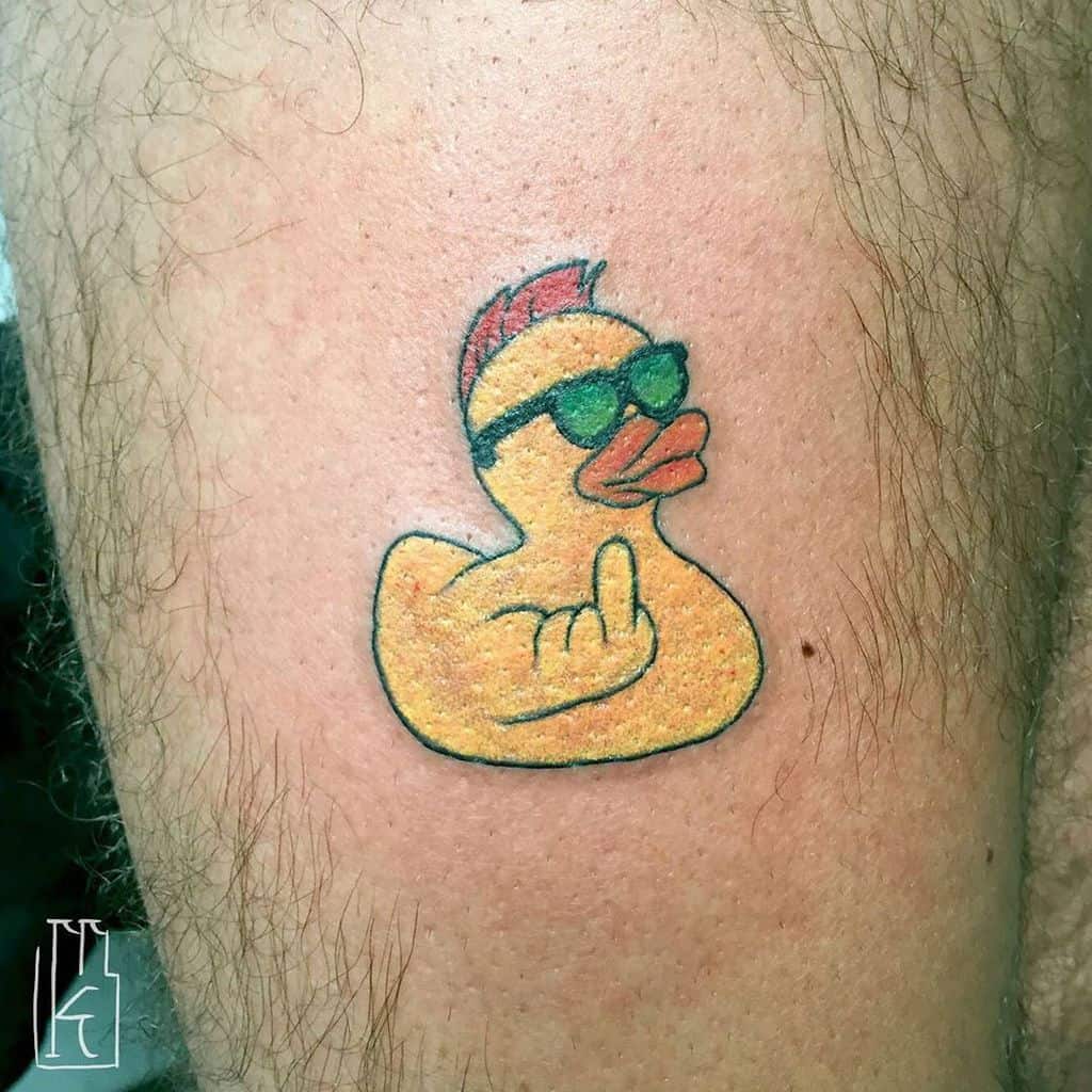A colorful tattoo of a rubber duck with sunglasses, a mohawk, and flipping the middle finger, giving off a rebellious and humorous vibe.
