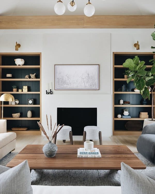 Modern living room with symmetrical built-in shelves, a black fireplace, and wooden accents.