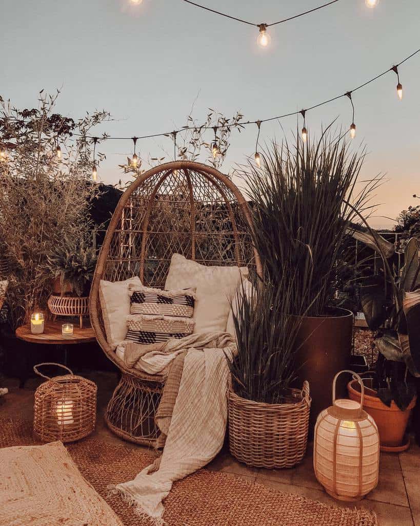 Boho-style patio with wicker egg chair, cozy cushions, lanterns, and string lights at sunset.