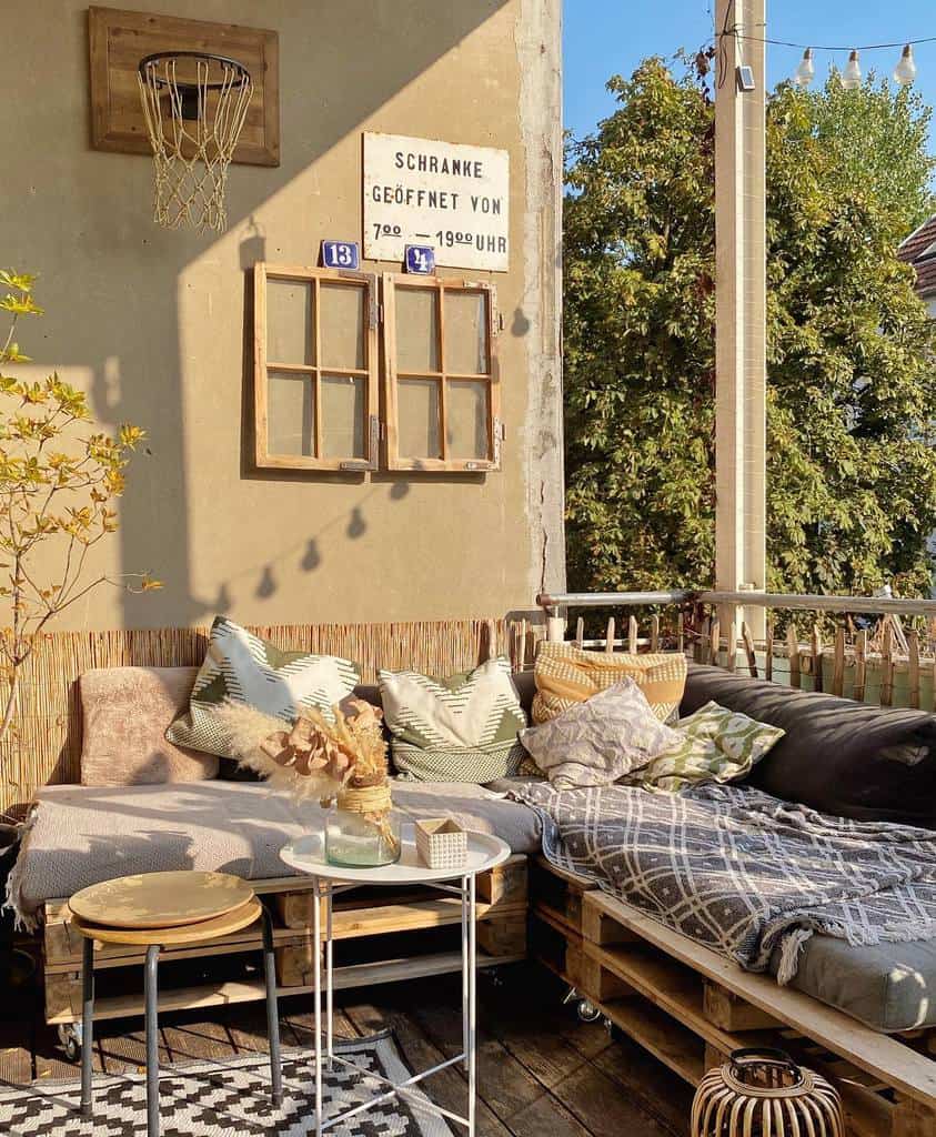 Rustic balcony with pallet seating, colorful cushions, basketball hoop, and vintage wall decor.