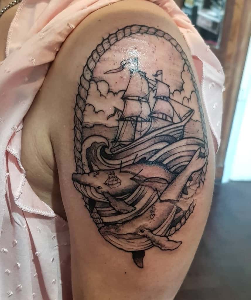 Black and gray nautical tattoo, featuring a sailing ship on ocean waves, a whale with miniature ships, and a rope border