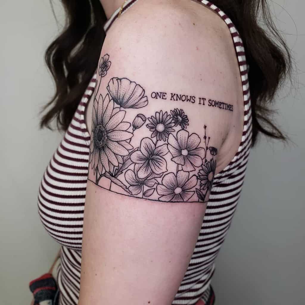Intricate floral armband tattoo, featuring detailed black and grey violet flower blossoms with fine-line shading and a quote reading 'ONE KNOWS IT SOMETIMES.'
