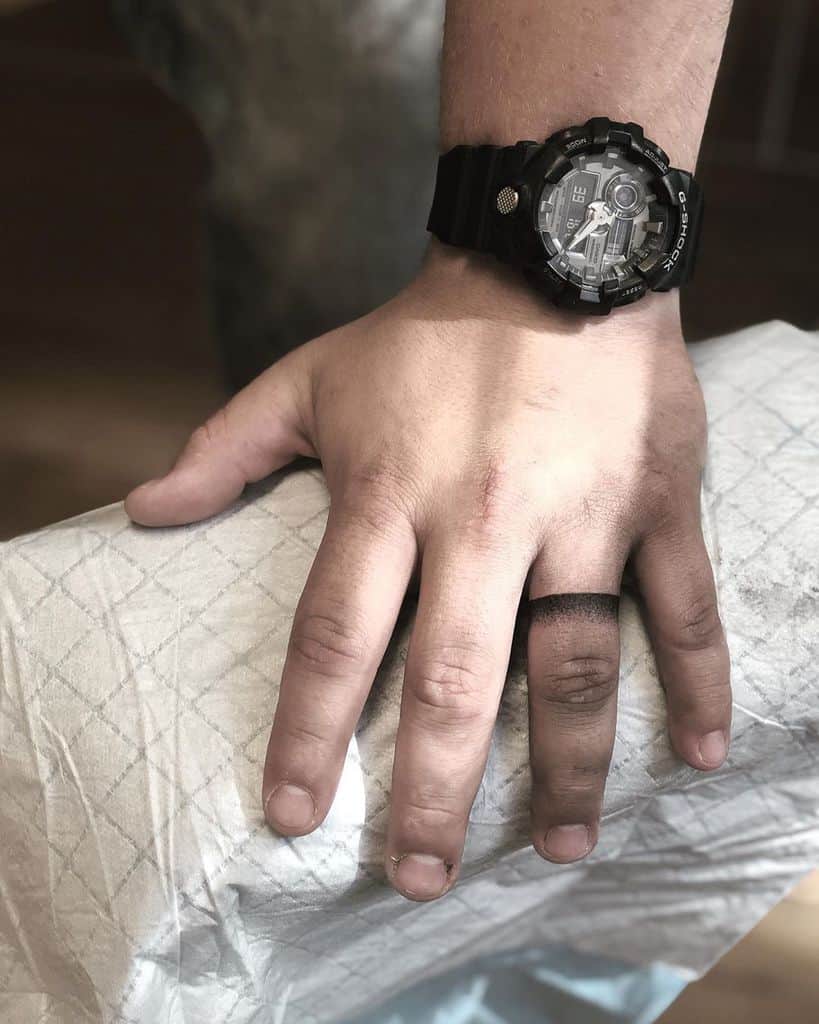 A tattoo of a black ring on the finger, symbolizing a wedding band, in a simple and bold design