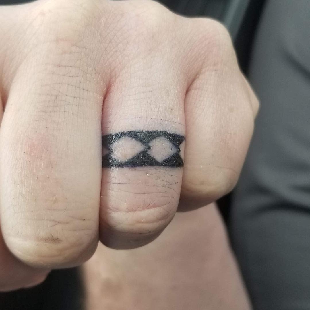 A tattoo resembling a ring, featuring a black band with diamond-shaped cutouts