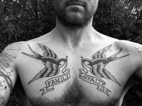 A man with chest tattoos of birds holding the words "FAMILY" and "LOYALTY" banners