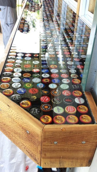 Bar top made of beer caps encased in clear resin on a wooden frame.