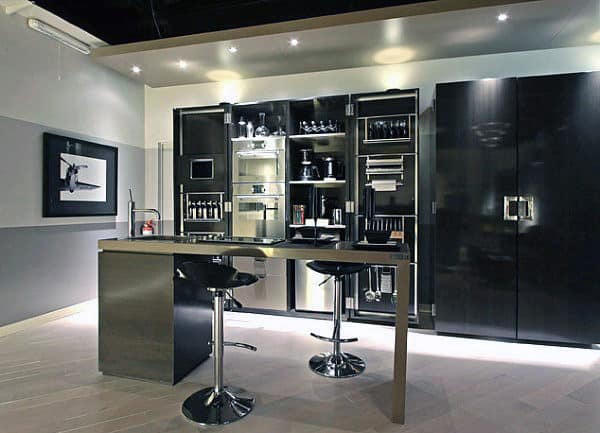 Modern kitchen with sleek dark cabinets, built-in appliances, and two barstools at the bar under spotlights
